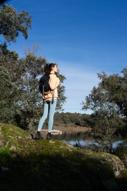 Woman hiking in nature alone with her backpack clipart