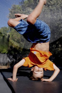 Çocuk trambolinde baş aşağı zıplıyor.