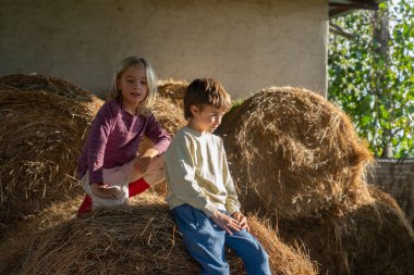 Çiftlikteki samanlıkta oturan iki çocuk