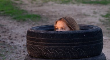 Boy playing hide and seek in some tire wheels clipart