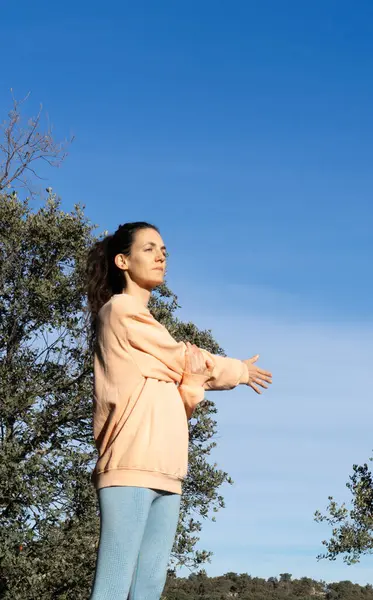 stock image Woman stretching shoulders after exercising in nature dressed in peach color