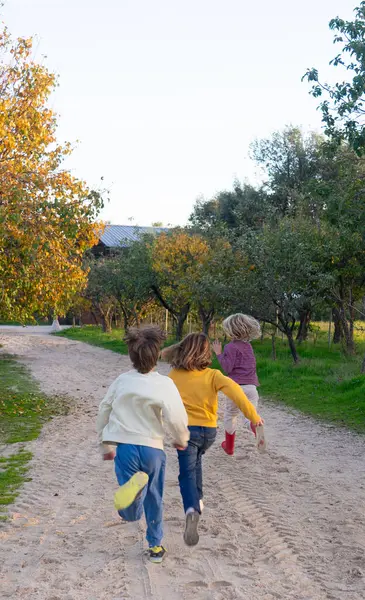 Three children running along a path through the countryside