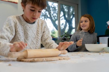 İki kardeş evde pizza pişiriyor.