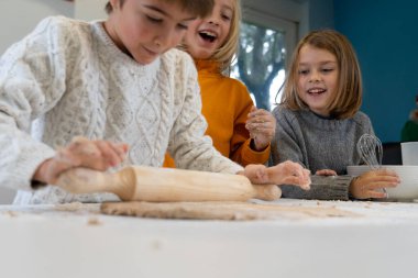 Çocuklar evdeki mutfakta ev yapımı pizza hamuru yoğuruyorlar.