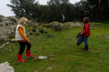 Plastikten doğayı temizleyen iki çocuk.