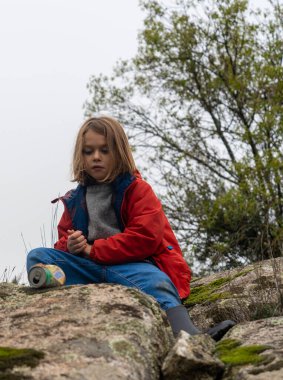 Doğadaki çocuk tarlada yatan paslı bir kutuya bakıyor.