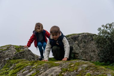Çocuklar doğada kayaların üzerinde oynuyorlar.
