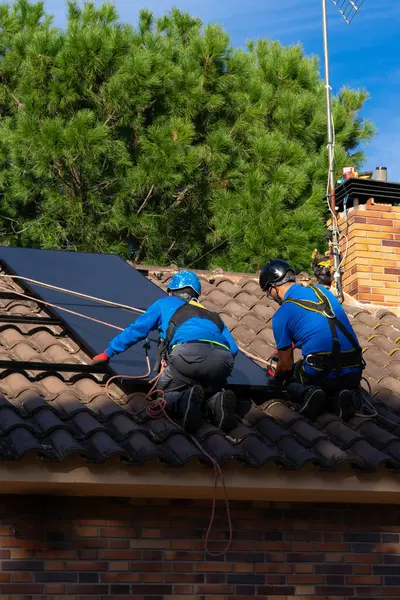 Two men installing solar panels on a house. Renewable energy. Solar energy
