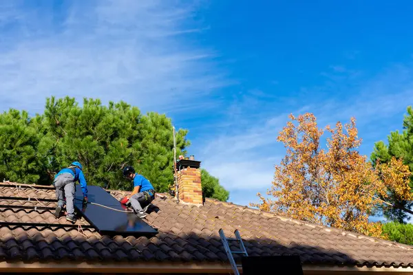two men working to install solar panels on a house
