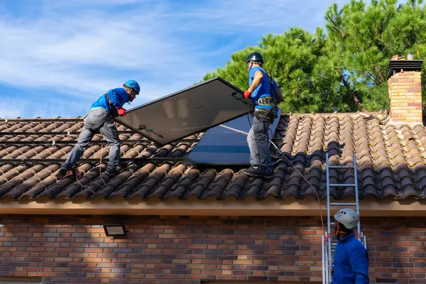 Three workers installing solar panels on a roof. Renewable energy