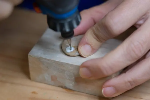 Woman's hands carving a stone with a rotary tool