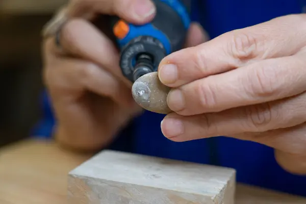 Artisan woman making a hole in a stone with a rotary tool seen up close