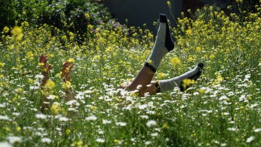 İlkbahar çiçek tarlasında çoraplı çocuk elleri ve ayakları. Bahar arkaplanı