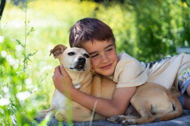 Kafkasyalı bir çocuk köpeğini kucaklıyor.