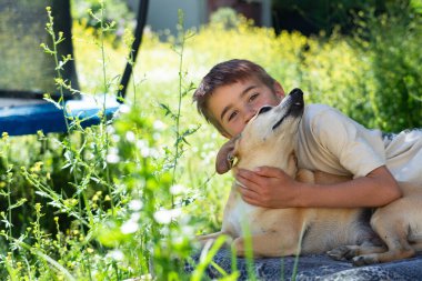 Baharda köpeğiyle birlikte evinin bahçesinde bir çocuk.
