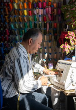 Dikiş makinesiyle dikiş diken terzi yaratıcı bir dikiş atölyesinde.