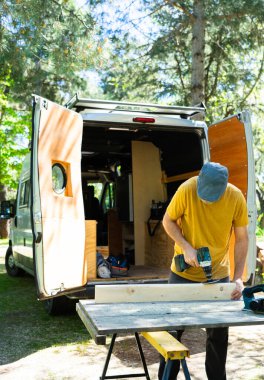 Man preparing a piece of wood to customize a camper van clipart