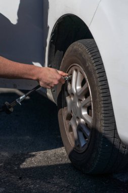Yakından görülen bir adamın eli araba lastiğini şişiriyor. Araba bakımı