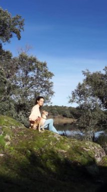 Doğada köpeğiyle oturan bir kadın