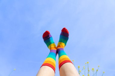 Arka planda mavi gökyüzü olan LGBTIQ marka çoraplı ayaklar