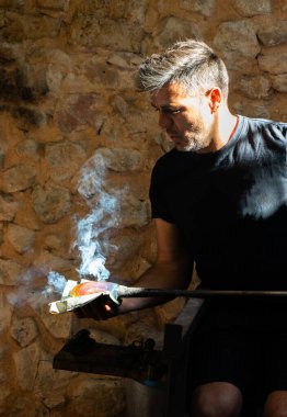 Esnaf atölyesinde cam bir parça yapıyor.