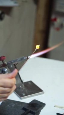 Cam üfleme atölyesinde pürmüzle cam bir mücevher yaratmak.