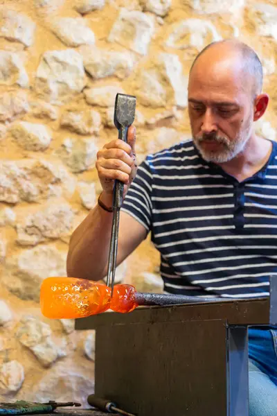 Stock image Artisan man shaping a blown glass vase in an artisanal glass blowing workshop