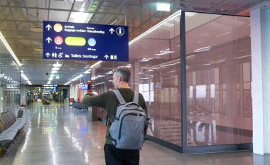 Havaalanında saatine bakan bir adam. Gecikmeli uçuş