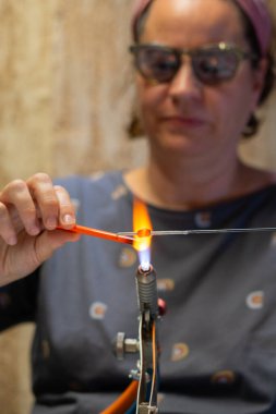 Esnaf atölyesinde cam bir mücevher yapıyor.