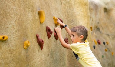 8 yaşında bir çocuk kopya alanı olan bir duvara tırmanıyor.