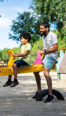 Latin bir baba ve oğlu oyun parkında birlikte oynuyorlar.