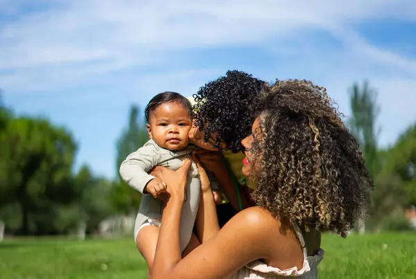 Stock image Latin family with afro hair of mother, child and baby. The boy giving the baby a kiss