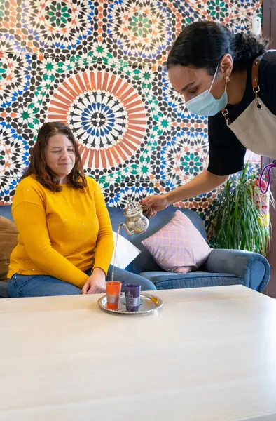 stock image Caucasian tourist woman in a tea shop in Morocco and a Moroccan woman serving her tea