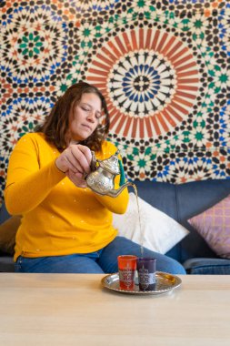 Fas çay dükkanında nane çayı dolduran kadın.