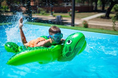 8 yaşında beyaz bir çocuk yaz günü havuzda kaplumbağa yüzme gözlüğü ve yüzme gözlükleriyle oynuyor.