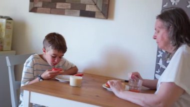 Büyükannem ve torunum evde tipik bir İspanyol kahvaltısı yapıyorlar.