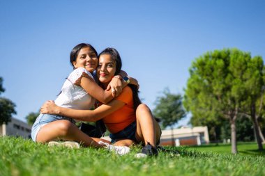 Perulu iki Latin kız kardeş açık hava parkında sarılıyorlar.