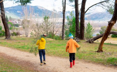 İki tanınamaz çocuk soğuk bir günde doğada oynuyorlar.