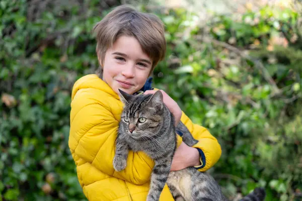 stock image Portrait of a boy in a yellow coat and his cat in his arms