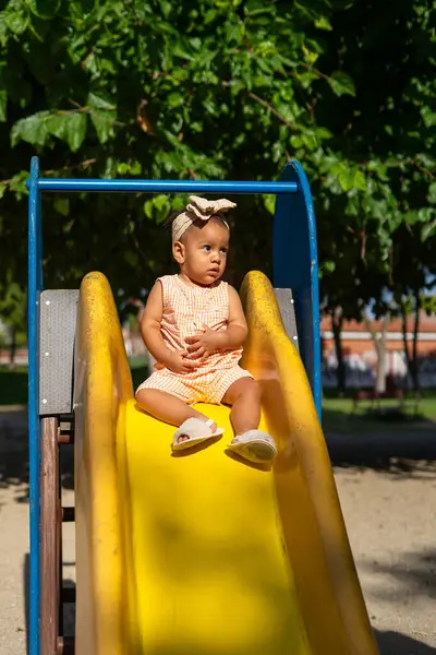 stock image 1 year old Latina baby at the top of a slide in a playground