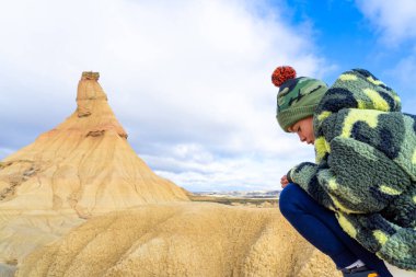 Çocuk çöl manzarasında oturuyor. Bardenas Reales, Navarra, İspanya
