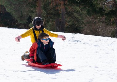 Beyaz çocuklar bir kış günü dağlarda karda birlikte kayıyorlar.
