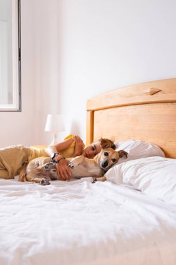 Kafkas çocuk 8 yaşında, küçük köpeğiyle yatakta yatıyor. Evcil hayvanlarla yatmak.