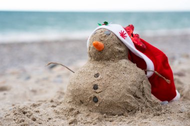 Noel günü Noel Baba şapkasıyla plaj kumundan yapılmış kardan adam.
