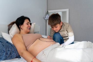 Boy painting his pregnant mother's belly at home clipart