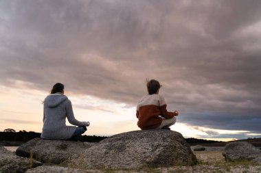Tanımlanamayan anne ve oğul gün doğumunda fotokopi uzayı ile bir gölde meditasyon yapıyorlar.