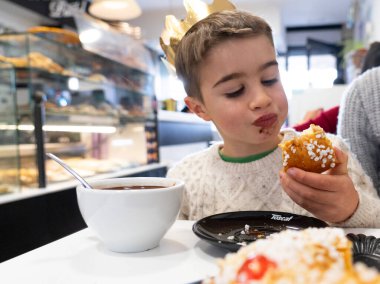 Pastanede Noel 'de Roscon de Reyes çikolatası yiyen beyaz bir çocuk. İspanyol geleneği. 6 Ocak