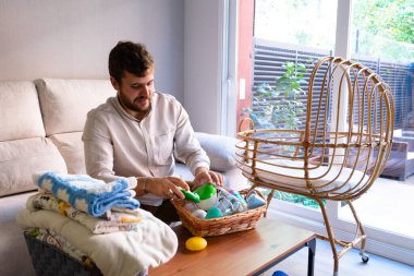 Caucasian man preparing bottles and clothes for his future baby clipart