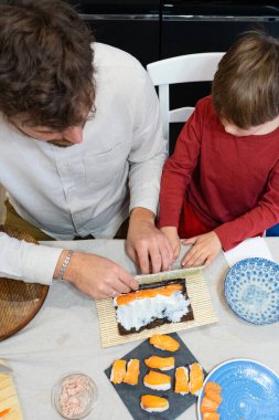 Kafkasyalı baba ve oğlu evde suşi hazırlıyorlar.