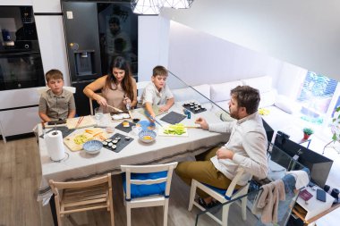Aile, modern bir mutfakta birlikte yemek masasında suşi yapmaktan hoşlanıyor.